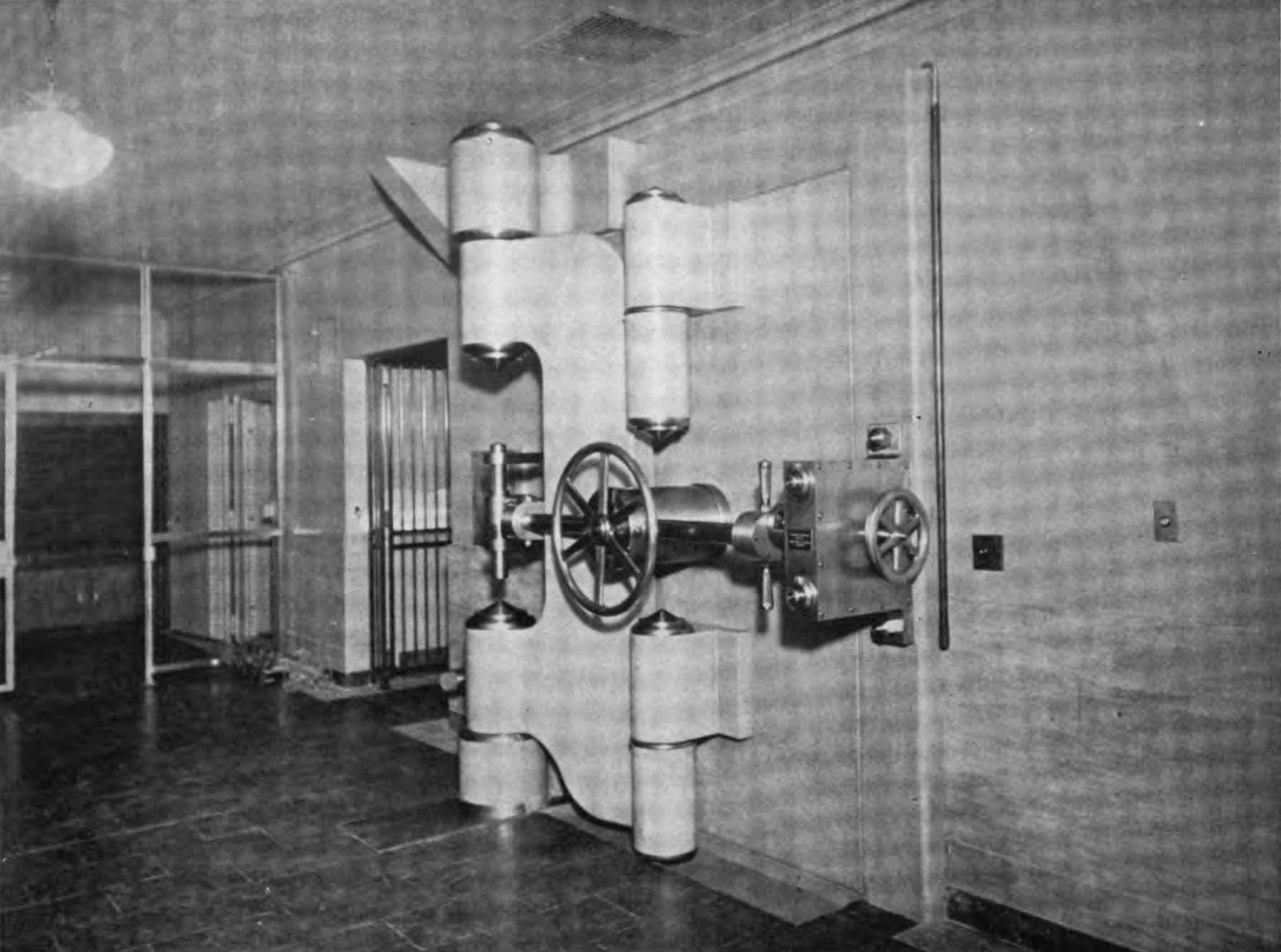 A round steel vault door on heavy hinges, standing open in a stone hall